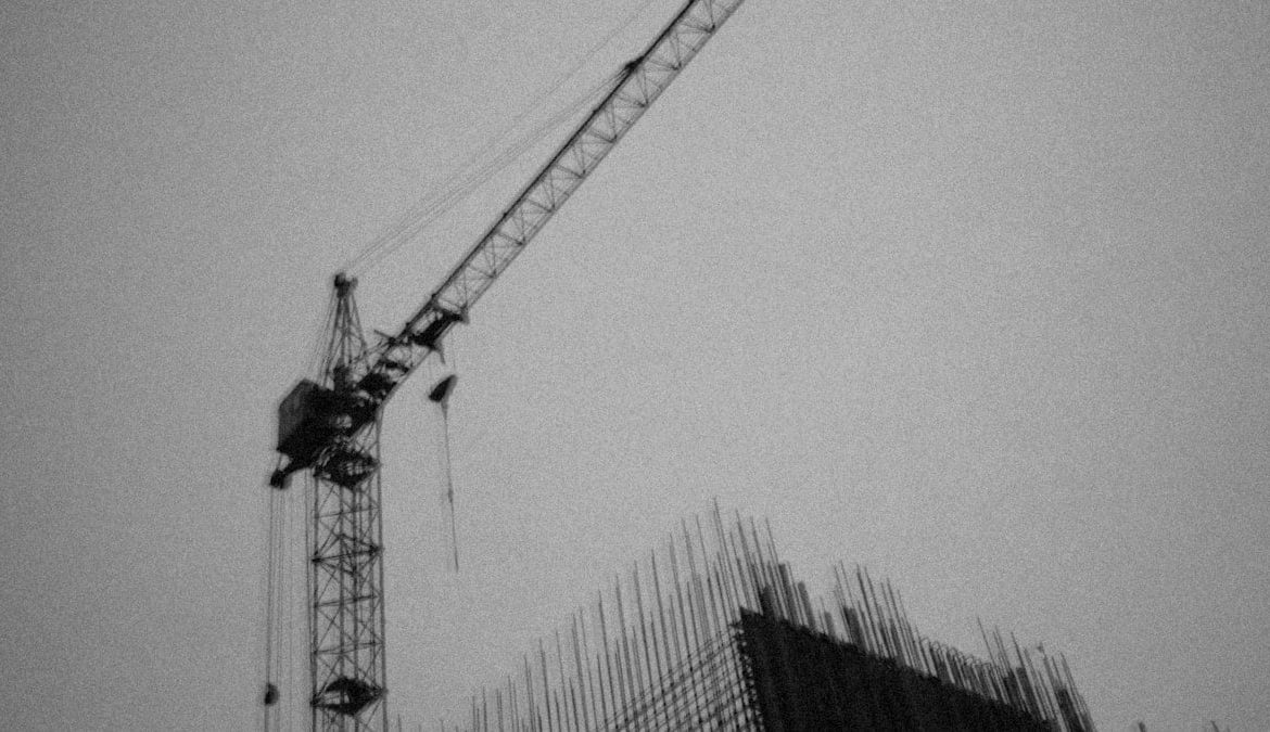 a crane is standing next to a building under construction